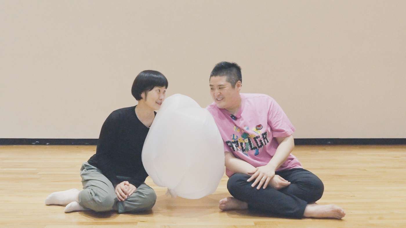 이윤정과 김시원이 풍선처럼 공기가 들어간 비닐봉지를 둘 사이에 두고 눈을 맞추며 대화를 나누고 있다.